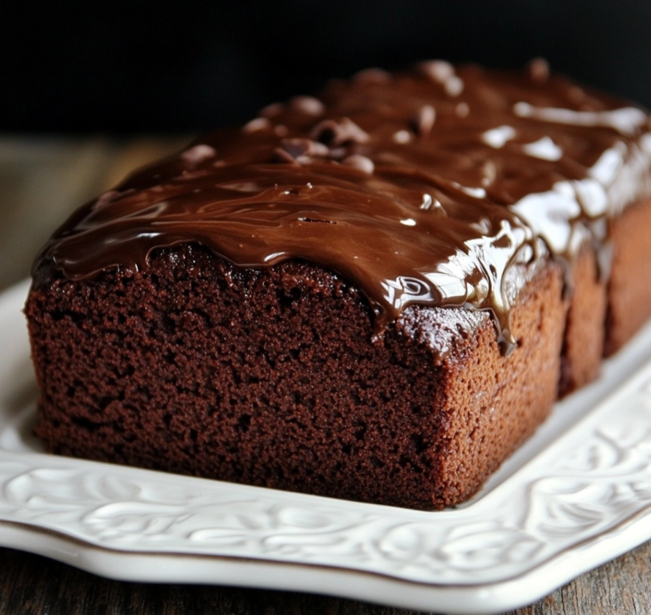 Chocolate pound cake served on a plate with a slice cut to reveal its moist texture.