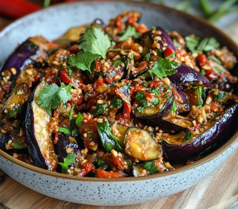 Thai aubergine recipe with tender eggplants in a creamy coconut curry sauce, garnished with fresh Thai basil and red chili.