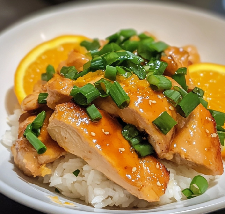 Sweet and tangy orange chicken served with rice and garnished with green onions.